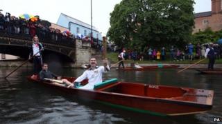 Torchbearer carrying Olympic flame on a punt