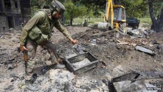 An Indian soldier searches for the bodies of suspected militants in the rubble of a house after a gun battle in Baban, 90km (55 miles) north of Srinagar