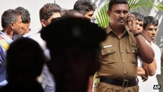 A Sri Lankan officer speaks on a mobile phone in front of the court house in Colombo, Sri Lanka, Friday, July 20, 2012.