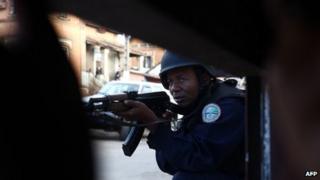 Police officer takes cover during a mutiny by troops at a military camp near Madagascar's main airport in Antananarivo on July 22