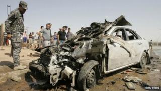 Iraqi policeman looks at car wrecked by bombing in Kirkuk (23/07/12)