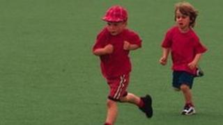 Two children running across school field
