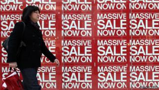Woman walks past sale signs