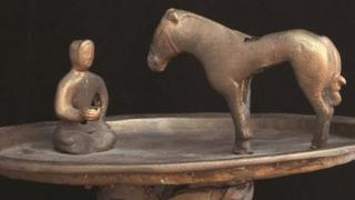 Raised bronze trays featuring a figure kneeling in front of a horse at the Smithsonian Freer and Sackler Asian Art galleries