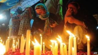 Relatives of fire victims light candles outside the Ali Enterprises garment factory in Karachi on September 13, 2012