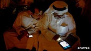 Kuwaitis check their messages at a sit-down protest in Kuwait City, 19 October