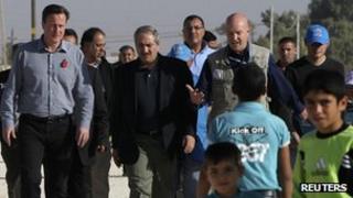 David Cameron walks with Jordanian Foreign Minister Nasser Judeh and United Nations High Commissioner for Refugees representative to Jordan Andrew Harper