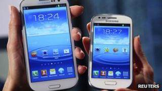 models hold a Samsung Galaxy S and a Galaxy S3 Mini (R) smartphones
