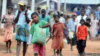 Internally displaced Tamils leave their camp with belongings in the northern town of Vavuniya (23 December 2009)