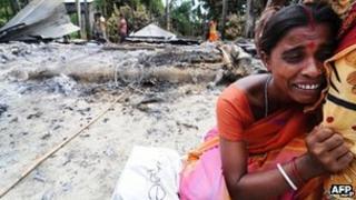 A Indian woman cries near the remains of her house burnt by rioters in Barpeta district in Assam on 29 August , 2012