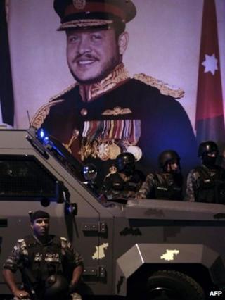 Riot police stand in front of a picture of King Abdullah II in Amman (13 November 2012)