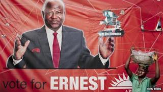 Fruit vendor in front of a campaign poster for incumbent President Ernest Bai Koroma, in Freetown, Sierra Leone
