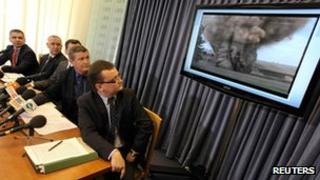 Members of Poland's Internal Security Agency (AWB) and the Prosecutors' Office sit in front of a screen showing evidence of a planned attack, during a news conference in Warsaw