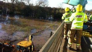 Bales of hay are lowered into a flooded field where 60 horses are stranded