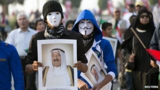 Youths wearing masks carry pictures of Kuwait's Emir during a celebration of the 50th anniversary of the constitution in Kuwait City (10 November 2012)