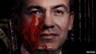 A photograph of Mexico's President Felipe Calderon is stained with paint to simulate blood, during a protest against his government, in power for six years, in Mexico City (28 November 2012)