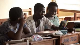 Three Ghanaian pupils - Ernestina Quaye (L), Narteh Andrews (C) and Lisa Okudzetp (R) - sit in a classroom in Accra on 1 December