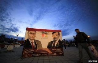 People walk past election posters in Bucharest, 3 December