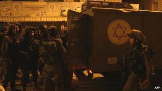 Israeli soldiers gather next to their vehicle during clashes with Palestinians in the West Bank town of Hebron, 12 December 2012