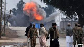 Onlookers observe a controlled blast at Peshawar airport perimeter