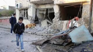 Boys walk past the scene of a bomb blast in Tuz Khurmatu, Iraq (17 December 2012)