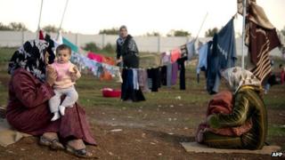 Mothers and children sit in a refugee camp near the Syrian city of Azaz (5 December 2012)