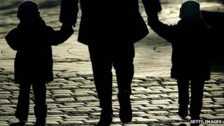 Silhouette of a woman holding hands with two children