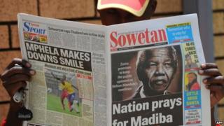 A man reads a local newspaper bearing in the headline a photo of former South African President Nelson Mandela, in Soweto on 10 December 2012 in Soweto