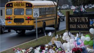 A school bus passes a makeshift memorial to the victims of the Sandy Hook Elementary School shooting as it takes students to Newtown High School 18 December 2012