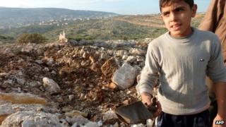 A boy holds up a piece of what rebel fighters said was the remains of a Scud-type missile that landed near the Sheikh Suleiman airbase near Darat Izza in northern Syria (13 December 2012)