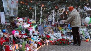 A persons tands in front of a memorial in Newtown