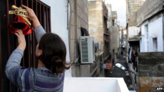 A Syrian woman hangs Christmas decoration at her home in Damascus