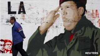 A man walks past a mural depicting President Hugo Chavez