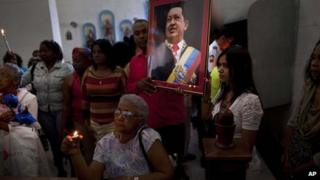 Venezuelan embassy workers in Cuba hold up picture of Chavez during a service for the sick, 8 January