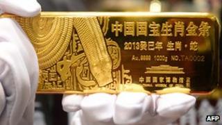 A worker holds a gold bar in a shop in China