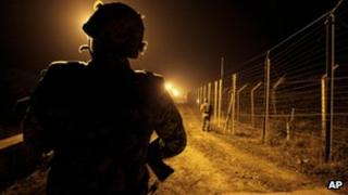An Indian Border Security Force (BSF) soldier stands guard during a night patrol near international border fencing at Suchet Garh in Ranbir Singh Pura, Thursday, 10 Jan 2013