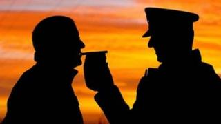 Silhouetted motorist gives a breath test to a police officer