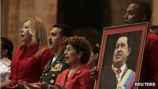 A man holds a picture of Hugo Chavez at a mass in Havana, Cuba
