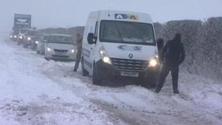 Cars waiting behind a van stuck in snow