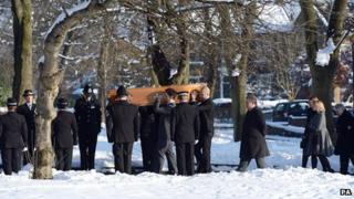 Police officers stand in a row as coffin is carried