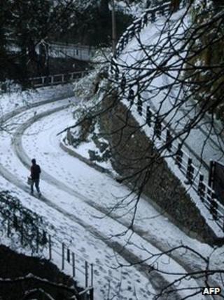 A man walks on a snow covered road after snowfall in the northern hill town of Shimla