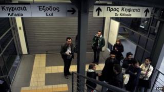 Commuters talk at the closed entrance to an urban rail station in Athens on January 24