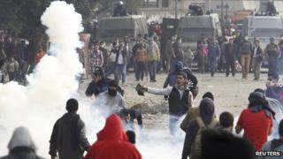 Protesters opposing Egyptian President Mohammed Morsi flee from tear gas fired by riot police during clashes along Qasr al-Nil bridge, Cairo