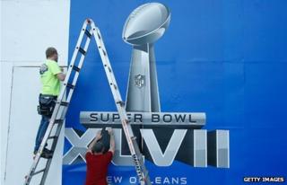 Workers finish a Super Bowl sign prior to the start of Super Bowl XLVII in New Orleans