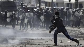 A protester opposing Egyptian President Mohamed Mursi throws stone at riot police during clashes in Cairo