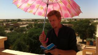 Thomas Fessy reading under umbrella