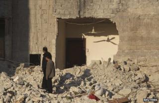 Men inspect the rubble of homes in Aleppo, Syria, 13 February