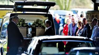 The two coffins are unloaded from the hearse
