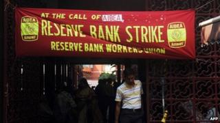 Indian employees stand near posters at the entrance to a bank during a two-day strike opposing the current UPA government’s economic policies in Kolkata