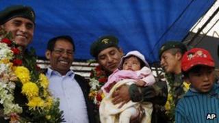 Bolivian soldier Alex Choque (c) holds his son as fellow soldier Jose Luis Fernandez (l) and Augusto Cardenas (r) look on